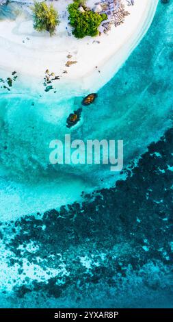 Le splendide acque turchesi si infrangono dolcemente contro le incontaminate sabbie bianche dell'isola di Koh Munnork. Le piccole barche galleggiano pacificamente, circondate da vibranti barriere coralline e lussureggiante vegetazione in Thailandia. Foto Stock