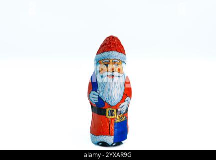 Una statuetta di cioccolato a tema Babbo Natale esposta su uno sfondo bianco. Il cioccolato è avvolto in lamina con un classico design Babbo Natale Foto Stock