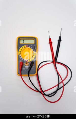 Multimetro giallo che mostra la misurazione elettrica con sonde su sfondo bianco Foto Stock