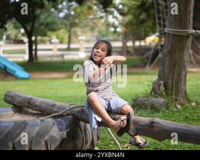 Una bambina carina che cammina su Balance beam nel parco all'aperto. I bambini giocano nel parco giochi durante le vacanze estive. Foto Stock