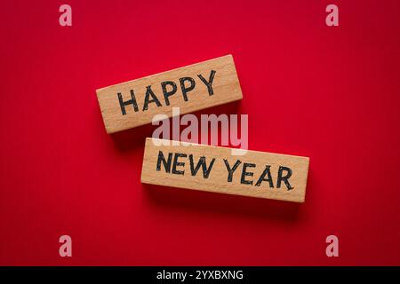 Felice anno nuovo scritto su blocchi di legno su sfondo rosso Foto Stock