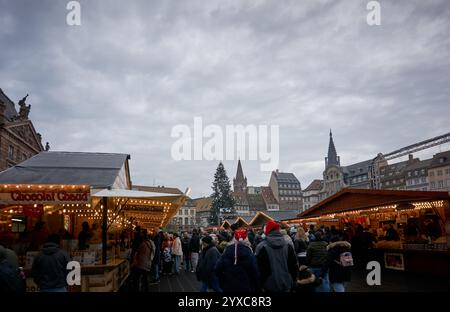 Strasburgo, Francia - 14 dicembre 2024: Veduta del mercato di Natale più antico del mondo con gente che fa shopping e acquista regali tradizionali. Foto Stock