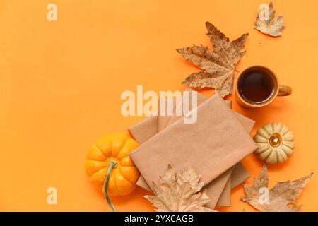 Composizione con libri, tazza di tè, zucca e foglie autunnali su sfondo colorato Foto Stock