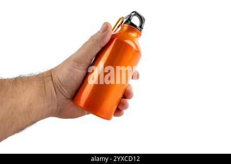 Una mano regge una bottiglia d'acqua arancione su sfondo bianco. La bottiglia è in metallo e ha un tappo nero. Foto Stock