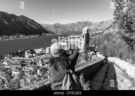 Cattaro, Montenegro - 14 febbraio 2024: Visitatore dai capelli ricci che scatta foto panoramiche della baia di Cattaro dal castello di Cattaro. Foto Stock