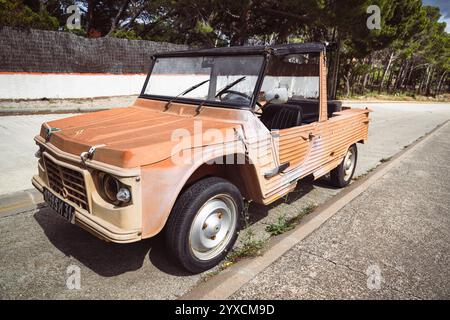 Un'antica auto Citroën Méhari Cabriolet color arancio parcheggiata su una strada di fronte a pini al sole sulla costa mediterranea Foto Stock