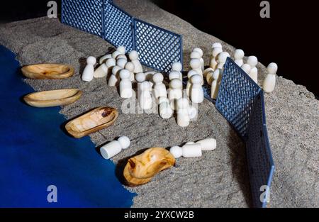 Statuette in legno dietro recinzioni con barche sulla sabbia Foto Stock