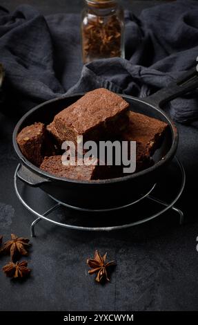 Pezzi di brownie al forno in una padella nera di metallo sul tavolo Foto Stock