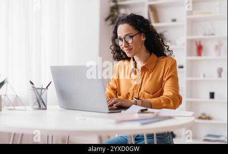 Donna del Medio Oriente che usa il laptop che lavora in linea seduta in ufficio Foto Stock