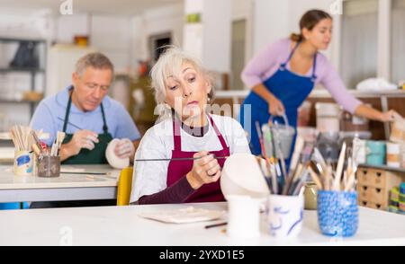 vasaio femmina dipinge vaso finito in bianco Foto Stock