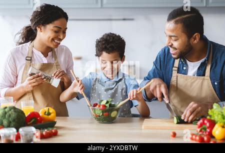 Cucinare insieme in famiglia in un ambiente di cucina allegro con verdure fresche Foto Stock