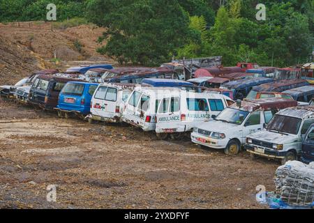 Balikpapan, Indonesia - 19 novembre 2024. Una fila di ambulanze abbandonate in una discarica, che mostrano i dettagli del suo deterioramento e del suo decadimento. Foto Stock