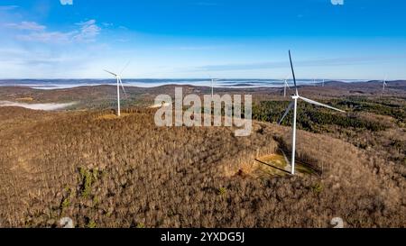 Un parco eolico in cima alla montagna con turbine eoliche in una giornata prevalentemente soleggiata. Foto Stock