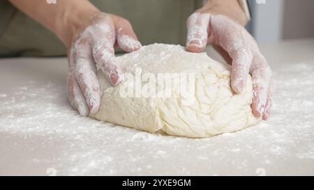 Mani che modellano l'impasto in palla a mano. Lo chef prepara l'impasto per cuocere il pane per pizza nel ristorante, cuocere. Foto Stock