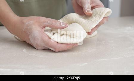 Mani che modellano l'impasto in palla a mano. Lo chef prepara l'impasto per cuocere il pane per pizza nel ristorante, cuocere. Foto Stock