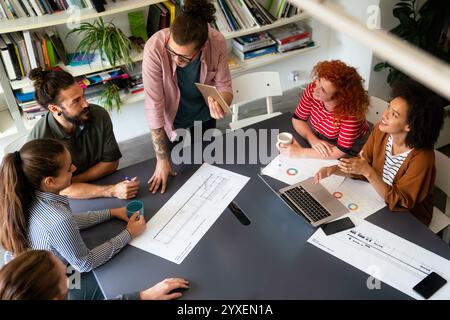 Diversi dipendenti riuniti in ufficio si divertono durante il brainstorming e discutono di nuove idee Foto Stock