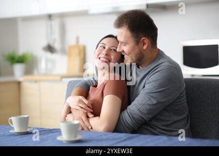 Felice coppia interrazziale che flirta in cucina guardandosi a casa Foto Stock