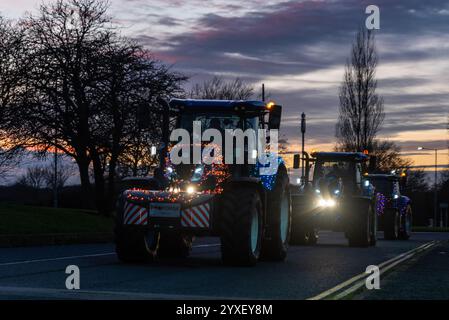 Trattori decorati con luci festive all'evento natalizio Charity Tractor Run di Basildon, Essex, Regno Unito. Crepuscolo Foto Stock