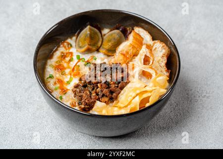 Porridge di riso o congee con maiale sminuzzato, uovo secolare e cakwe in ciotola Foto Stock