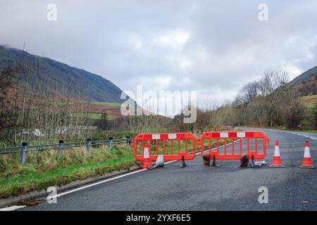 Barriere arancioni e bianche che indicano una strada chiusa dopo danni causati da tempeste in Cumbria, Regno Unito. Foto Stock