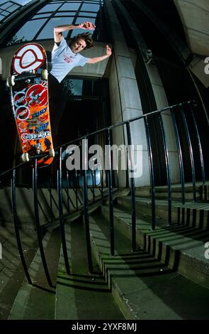 Uomo skateboard lungo il corrimano (grandangolare) Foto Stock