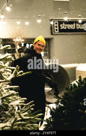 Uomo che sceglie un albero di Natale da una vasta selezione di pini Foto Stock