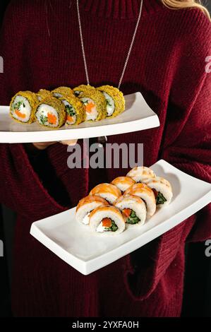 sushi roll con gamberi e panini al forno con pesce rosso sui piatti Foto Stock