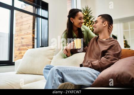 Una bella coppia condivide momenti caldi nella loro casa decorata durante le vacanze. Foto Stock