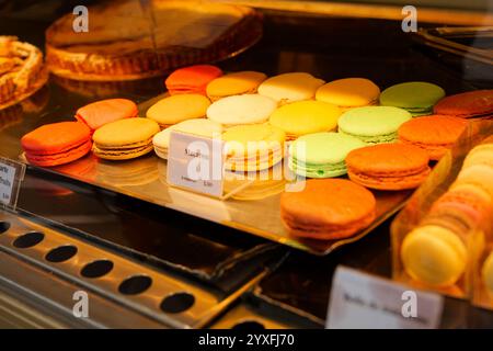 Macaroon colorati esposti in una panetteria, invitando i clienti a concedersi dolci durante un allegro pomeriggio Foto Stock