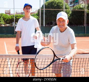 Nonno e nipote in posa sul campo da tennis Foto Stock