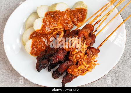 Maiale Satay o Sate Babi. Satay di maiale servito con salsa di arachidi e fette di lontong o ketupat (torte di riso) Foto Stock