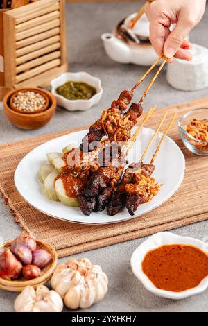 Maiale Satay o Sate Babi. Satay di maiale servito con salsa di arachidi e fette di lontong o ketupat (torte di riso) Foto Stock