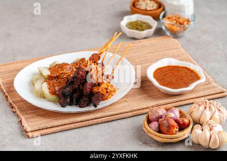 Maiale Satay o Sate Babi. Satay di maiale servito con salsa di arachidi e fette di lontong o ketupat (torte di riso) Foto Stock