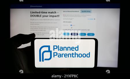 In questa immagine, una persona ha in mano un cellulare con il logo della Planned Parenthood Federation of America Inc. (PPFA) davanti alla pagina Web. Foto Stock