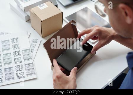 Confezionamento di smartphone nella confezione con etichette con codice a barre Foto Stock
