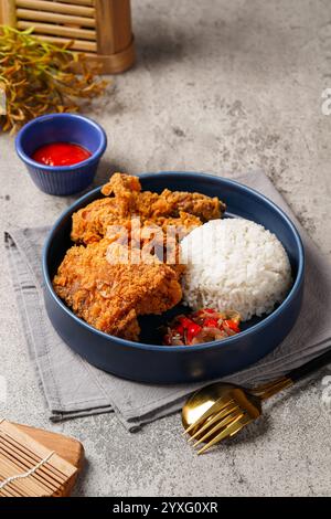 Ayam Geprek è un pollo fritto croccante con salsa di peperoncino sambal calda e piccante. Foto Stock