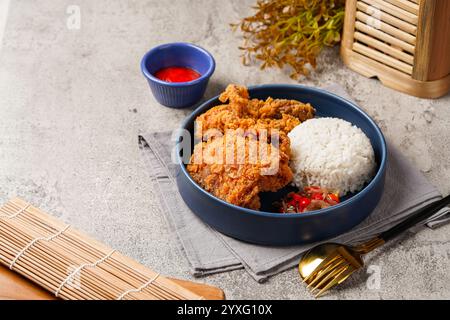 Ayam Geprek è un pollo fritto croccante con salsa di peperoncino sambal calda e piccante. Foto Stock