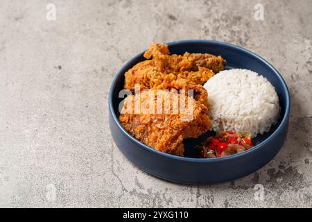 Ayam Geprek è un pollo fritto croccante con salsa di peperoncino sambal calda e piccante. Foto Stock