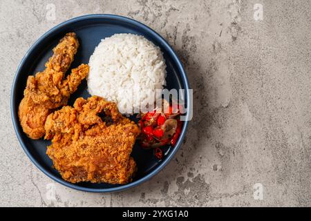 Ayam Geprek è un pollo fritto croccante con salsa di peperoncino sambal calda e piccante. Foto Stock