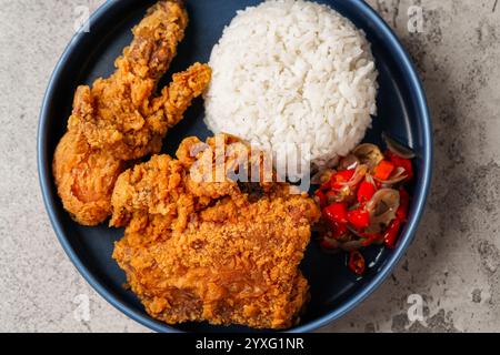 Ayam Geprek è un pollo fritto croccante con salsa di peperoncino sambal calda e piccante. Foto Stock