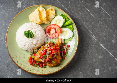 Il Nasi Ayam Geprek è un pollo fritto croccante con sambal bawang caldo e piccante. Servito con riso Foto Stock