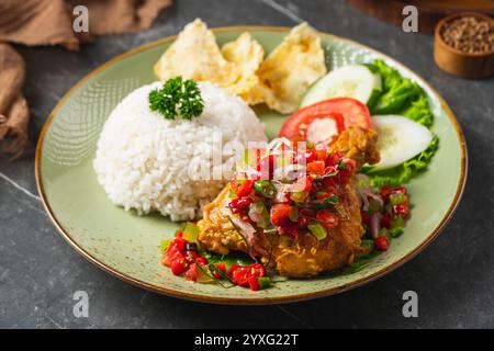 Il Nasi Ayam Geprek è un pollo fritto croccante con sambal bawang caldo e piccante. Servito con riso Foto Stock