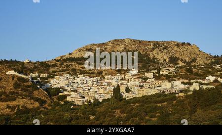 Piccolo villaggio incastonato in un paesaggio collinare con colline rocciose e fitte foreste, villaggi di montagna di Aperi e Volada, luce del mattino, Karpathos, Dodeca Foto Stock