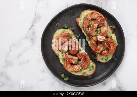 Panini con avocado e gamberi caramellati, microverdure, colazione, su un piatto, vista dall'alto, fatti in casa, niente persone Foto Stock