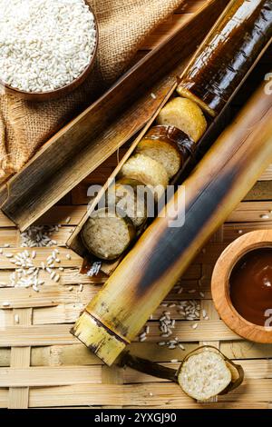 Lemang. Il riso glutinoso viene avvolto con foglie di lerek o di banana racchiuse in culme di bambù e cucinate a fuoco aperto. Foto Stock