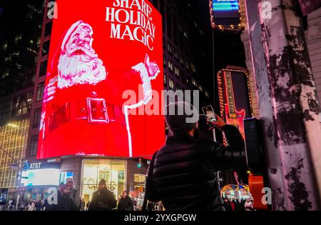 I visitatori di Times Square a New York mercoledì 4 dicembre 2024 camminano sotto diversi cartelloni pubblicitari digitali a tema natalizio che pubblicizzano Coca-Cola. (© Richard B. Levine) Foto Stock