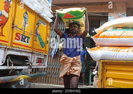 Un coolie che porta un sacco pesante sulla testa nel distretto George Town di Chennai, Tamil Nadu, India Foto Stock