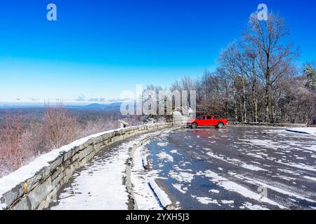 Un camion rosso solitario è parcheggiato nel parcheggio innevato del Turkey Creek che si affaccia sulla Cherohala Skyway in Tennessee durante l'inverno. Foto Stock