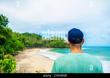 Vista posteriore dell'uomo turista che si trova sopra la spiaggia di sabbia tropicale con l'oceano turchese. Viaggiatore di sesso maschile che cammina fino alla spiaggia Freedom sull'isola di Phuket Foto Stock