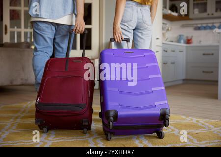 Vista rifilata della coppia che esce di casa con i bagagli pronti per le vacanze Foto Stock